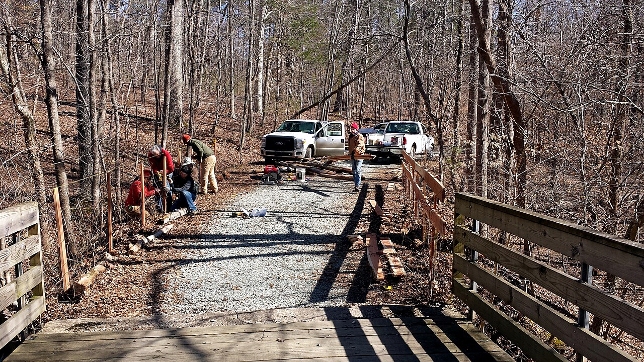 Fencing crew setting out posts and rails on a job with work utes parked behind